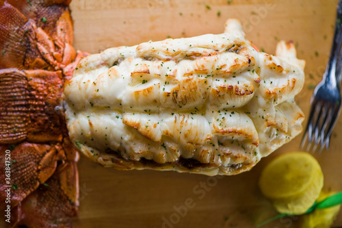 Fototapeta Naklejka Na Ścianę i Meble -  Lobster tail, served with drawn butter and lemon wedges. Maine lobster tail, classic American restaurant favorite. Seasoned with salt and pepper and garnished with Italian parsley.