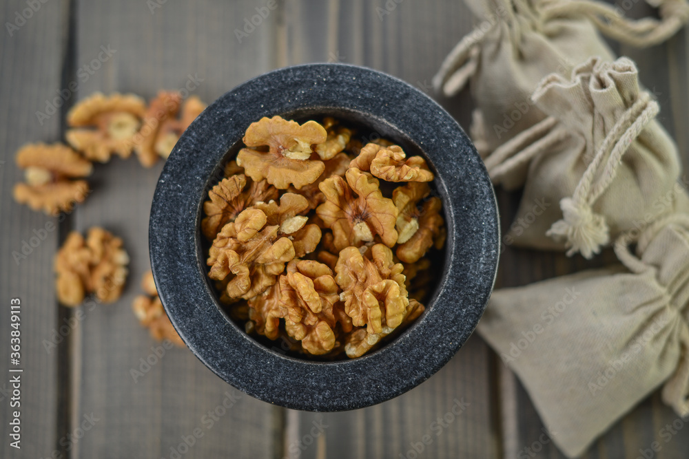 Obraz premium Walnuts in a granite bowl on wooden table
