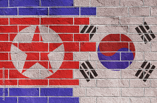 Flags of North and South Korea on bricks wall. Background on topic of international conflict