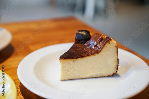 Basque Rare Cheesecake. A slice of cheese cake with burnt cake surface on white plate, at coffee cafe.
