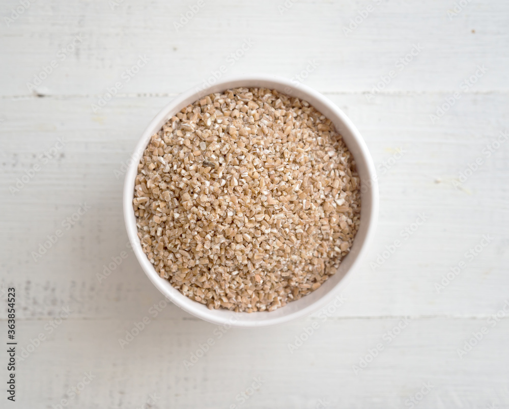 Wheat groats in a bowl on wooden background Wheat groats in a bowl on wooden background