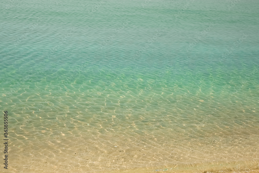 Sea background. Blue sea, sand and small pebbles. different color stripes of water and sand.