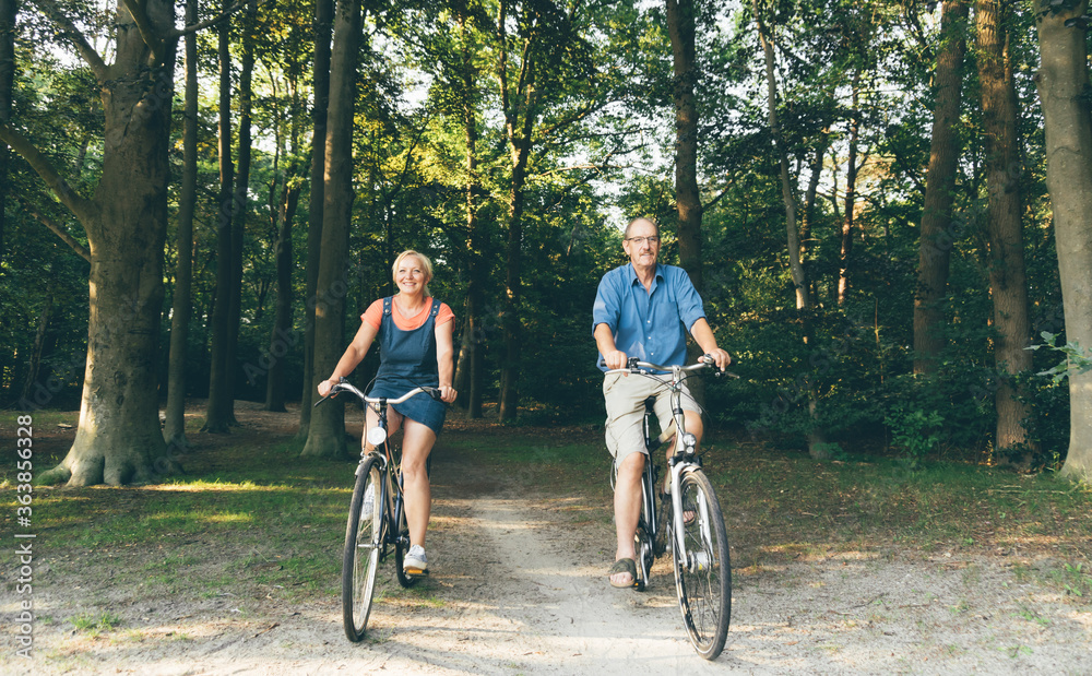 Active seniors riding bike in summer nature. Old people healthy lifestyle and sport concept