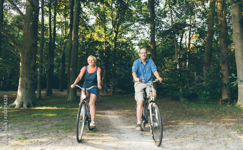 Active seniors riding bike in summer nature. Old people healthy lifestyle and sport concept