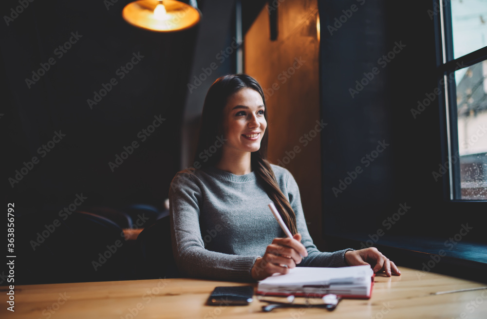 Charming brunette female journalist starting working day in coffee shop creating article sitting near window, dreamy hipster girl enjoying spending free time in cozy cafe interior noting ideas Charming brunette female journalist starting working day in coffee shop creating article sitting near window, dreamy hipster girl enjoying spending free time in cozy cafe interior noting ideas