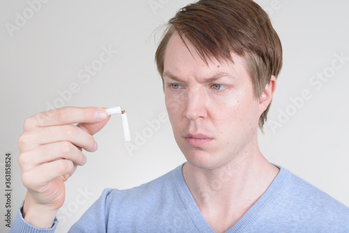 Portrait of young man looking serious while holding cigarette in half