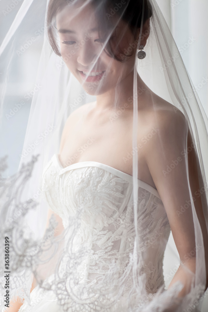 Asian women in white wedding dresses stand at the window waiting for the bridegroom's arrival, looking happy and happy Asian women in white wedding dresses stand at the window waiting for the bridegroom's arrival, looking happy and happy