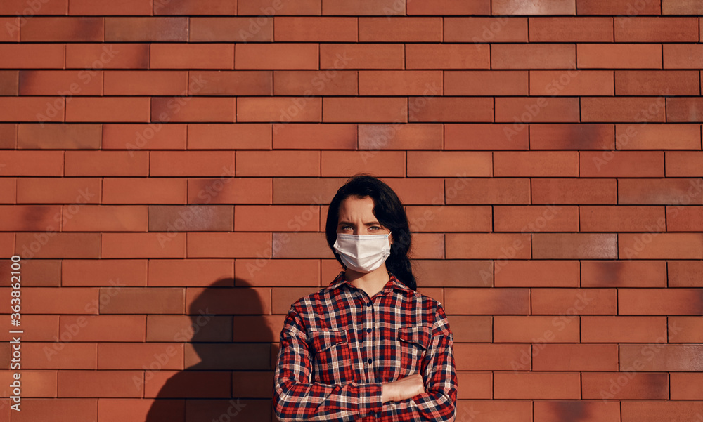 Naklejka premium Confident woman in mask against brick wall