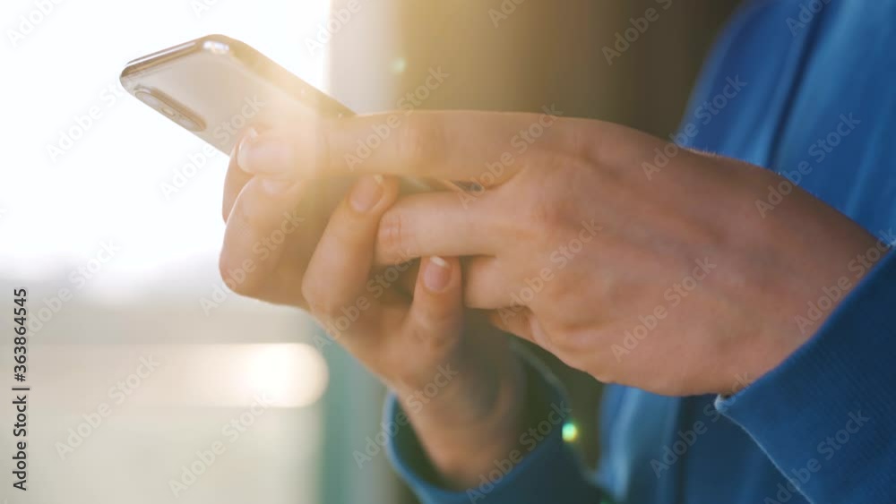 Female hands using smartphone against the setting sun. Female hands using smartphone against the setting sun.