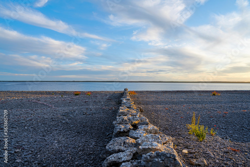 Stone wall on cobblestone beach with ocean background