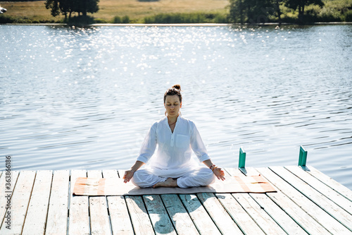 a young girl does yoga on a lake on a Sunny summer day, meditation, relaxation pose, Shavasana or dead man's pose, retreat in nature, peace, relaxation