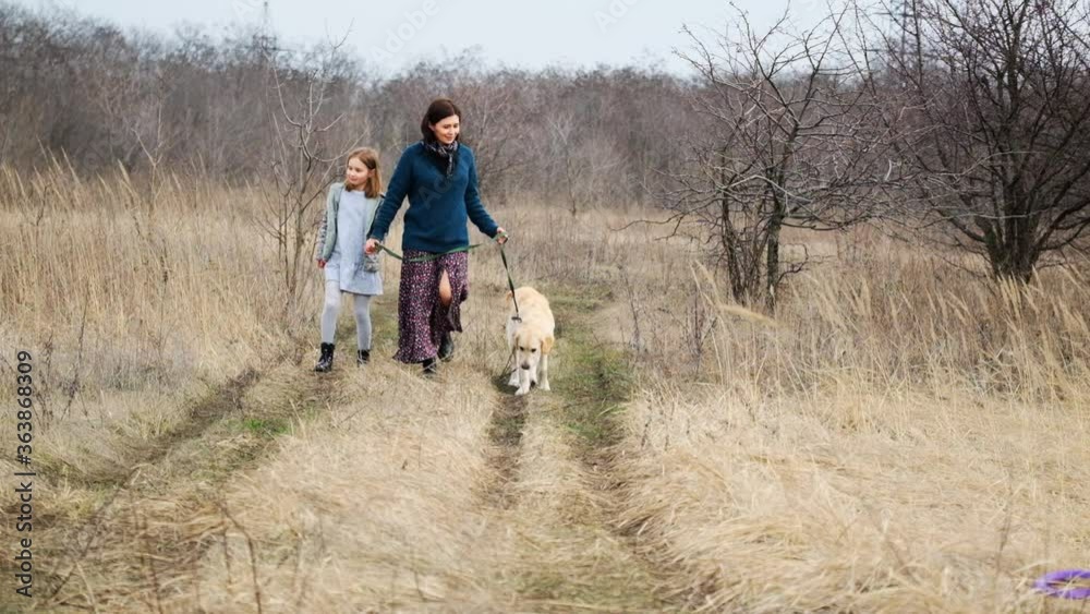 Woman and girl walking dog in early spring nature Woman and girl walking dog in early spring nature