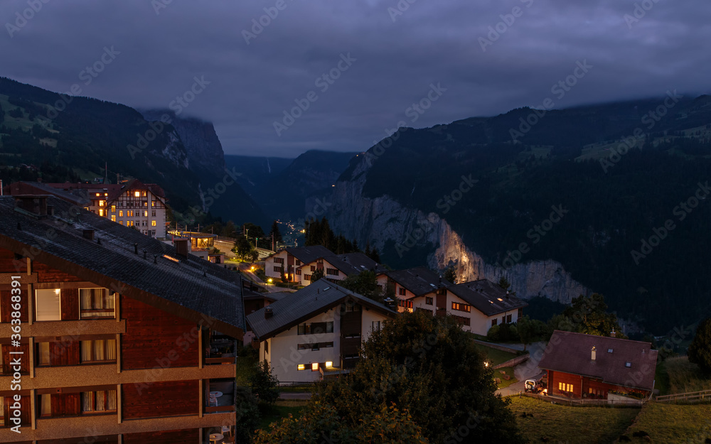 View on swiss alpine village Wengen and the cliffs of the Lauterbrunnen valley under cloudy skies. night landscape in summer