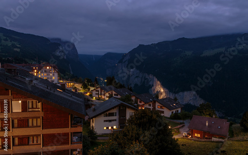 View on swiss alpine village Wengen and the cliffs of the Lauterbrunnen valley under cloudy skies. night landscape in summer