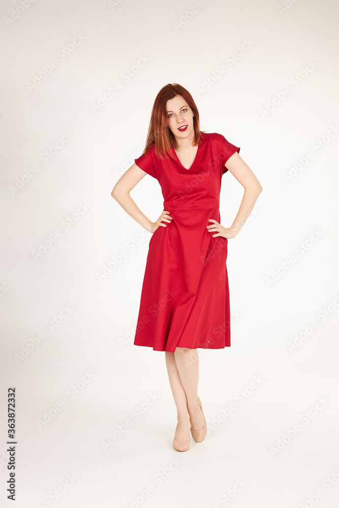 Smiling redhead girl on white background red dress