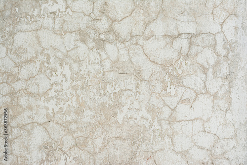 textured wall covered with cracked gray and white stucco © Anton