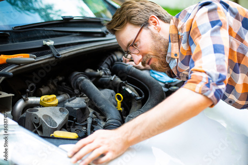 A man fixing a car on a sunny day. Self automobile repair.