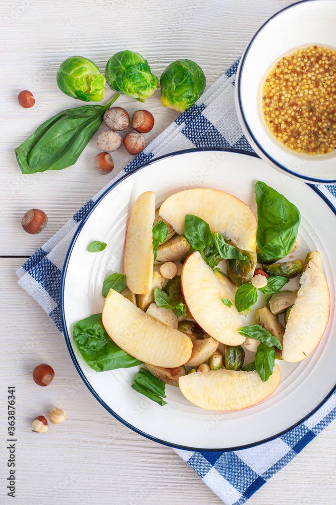 Summer salad of apples and brussels sprouts on a white wooden background. Vertical photo.