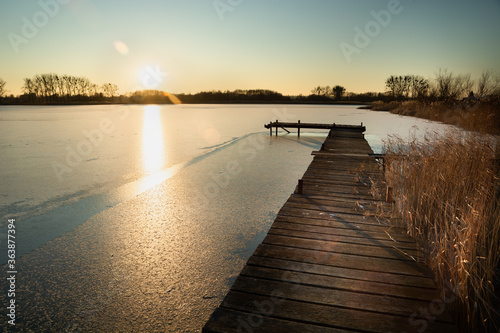 A wooden platform on a frozen lake and the sun over the horizon
