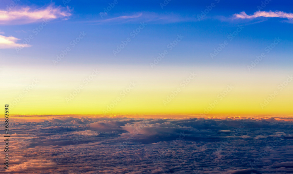 Top view of fluffy clouds on sunset sky view from flying airplane