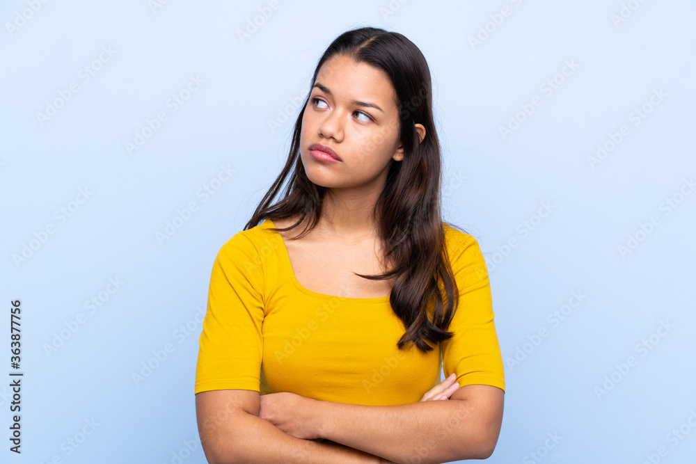 Young Colombian girl over isolated blue background thinking an idea