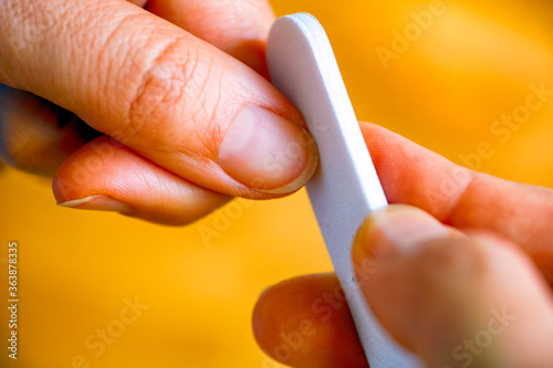 Woman using nail file on her fingernails.