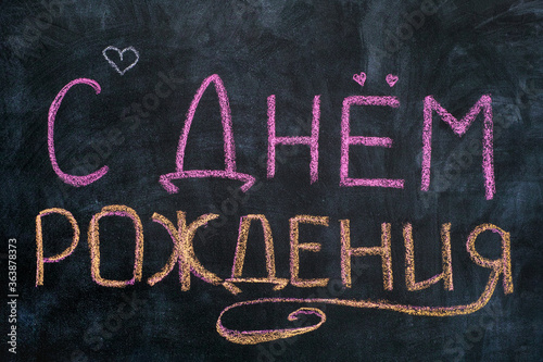 Words Happy Birthday written in Russian language on blackboard.