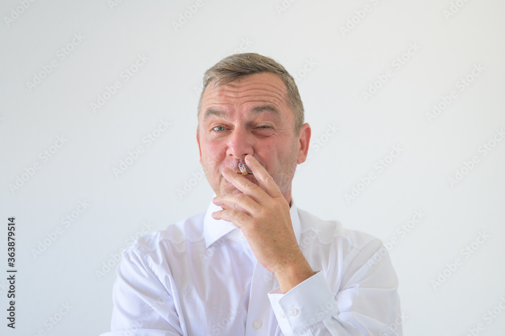 Middle-aged man squinting at camera while smoking Middle-aged man squinting at camera while smoking