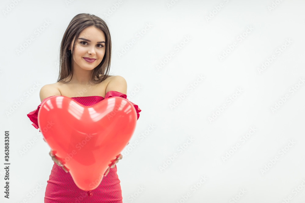 Smiling woman stands over white background with red heart-shape balloons in hands. Smiling woman stands over white background with red heart-shape balloons in hands.