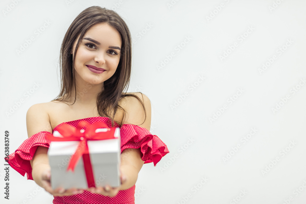 Joyful woman holding a gift box and smiling over a white background. Joyful woman holding a gift box and smiling over a white background.