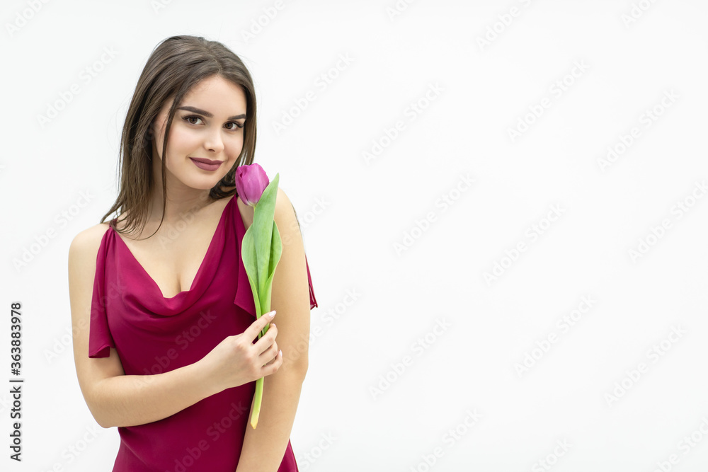 Young cute woman smelling pink tulip, slightly smiling at the camera, looking peacefull. Young cute woman smelling pink tulip, slightly smiling at the camera, looking peacefull.