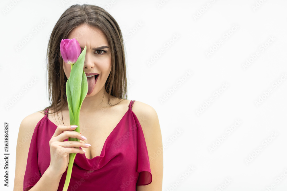 Cheerful lady fooling around hiding her eye behind a tulip flower and making silly faces. Cheerful lady fooling around hiding her eye behind a tulip flower and making silly faces.