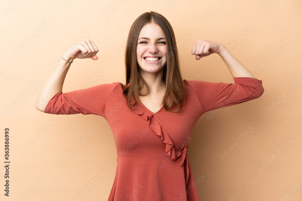 Young caucasian woman isolated on beige background doing strong gesture Young caucasian woman isolated on beige background doing strong gesture