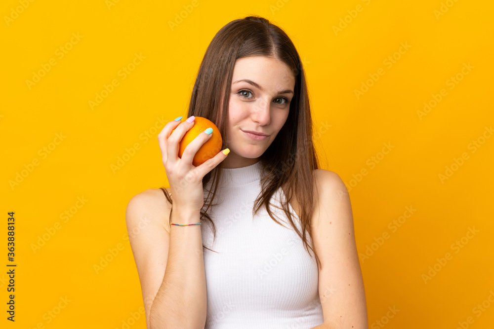 Young caucasian woman holding an orange isolated on orange background Young caucasian woman holding an orange isolated on orange background