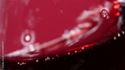 Close up swirling red wine in wineglass over red