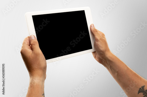 Close up male hands holding tablet with blank screen during online watching of popular sport matches, championships. Copyspace for advertising. Devices, gadgets, technologies concept.