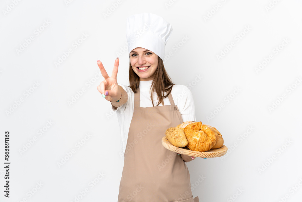 Young woman in chef uniform isolated on white background smiling and showing victory sign