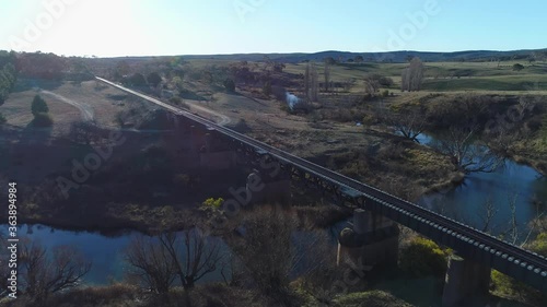 Aerial flyover railway bridge in Australian rural landscape, across river, clear winter day.