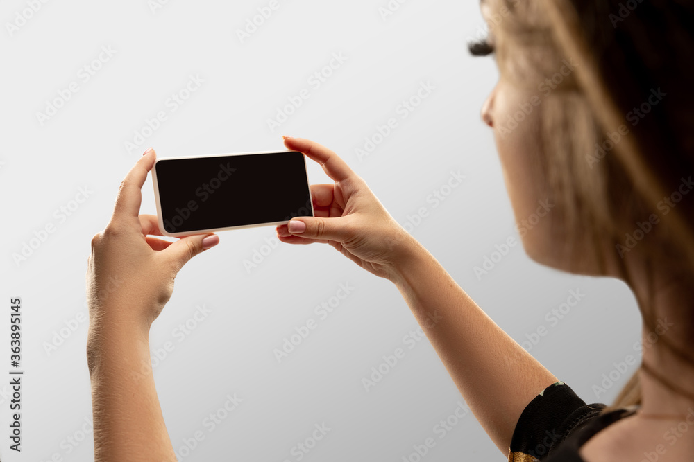 Looking attented. Close up female hands holding smartphone with blank screen during online watching of popular sport matches, championships. Copyspace for ad. Devices, gadgets, technologies concept.
