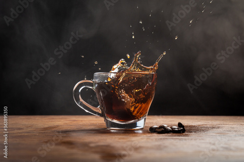 Splashing cup of coffee with beans on a wooden table photo