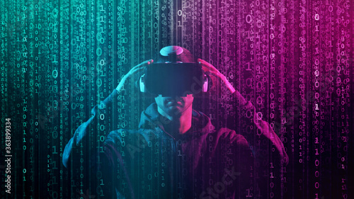 Portrait of a man in virtual reality helmet over abstract digital background. Obscured dark face in VR goggles. Internet, darknet, gaming and cyber simulation.