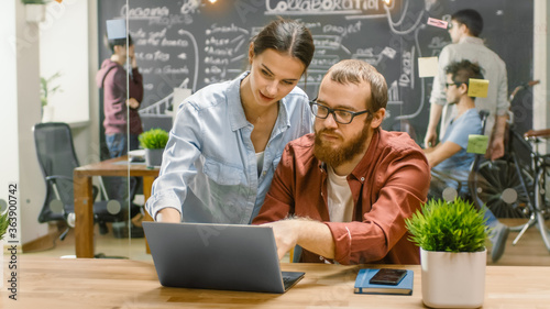 Wallpaper Mural Female Designers Talks Male Developer About Ongoing Project while He Works on a Laptop. In the Background Stylish Young People in Trendy Office Environment. Torontodigital.ca