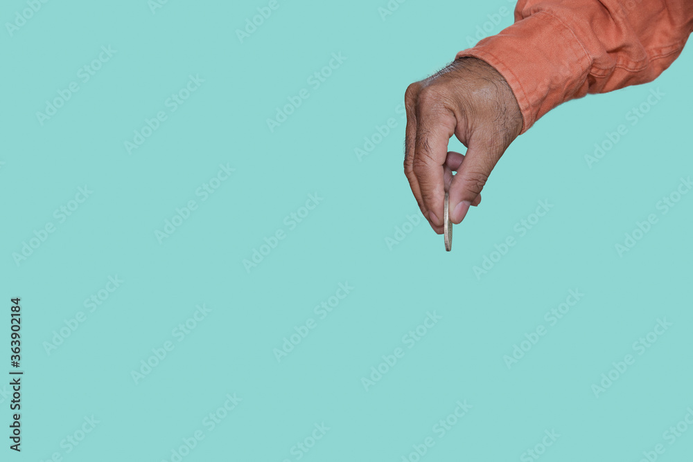 Fototapeta premium Hand picking coin-operated isolated on blue background minimal or copy space.