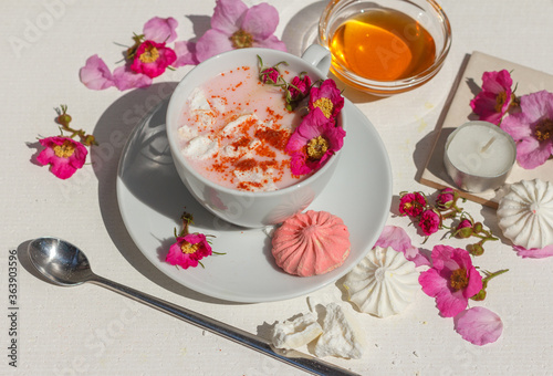 Pink moon milk with spices, marshmallows and wild rose flowers. Close up on a white background
