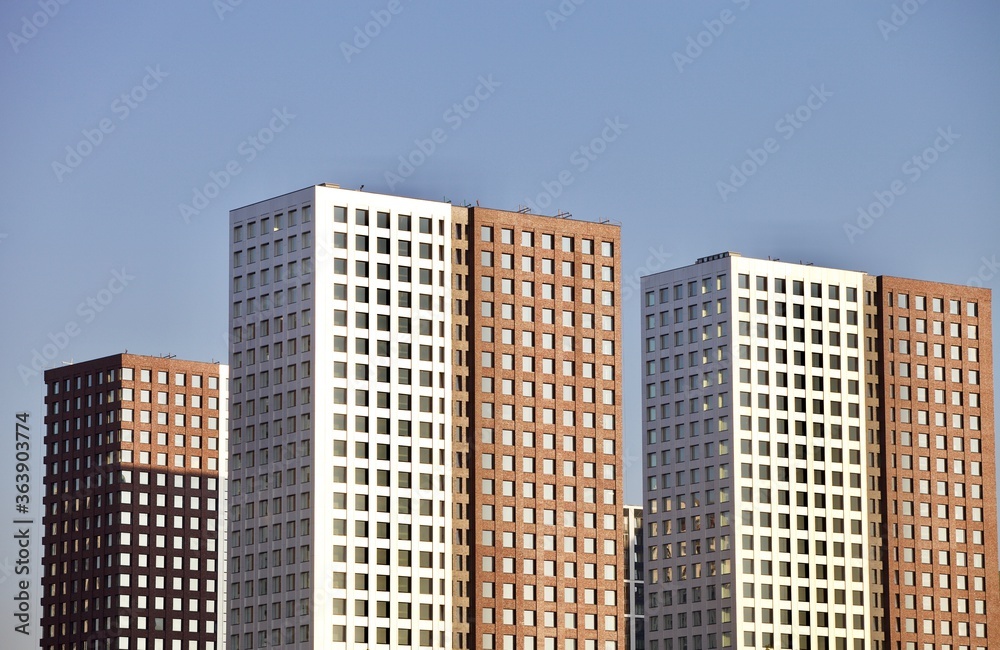 Obraz premium Residential skyscrapers on clear blue sky background. Commercial real estate. Modern residential city district. Apartment buildings architecture. New Property For Sale. New buildings exterior design.