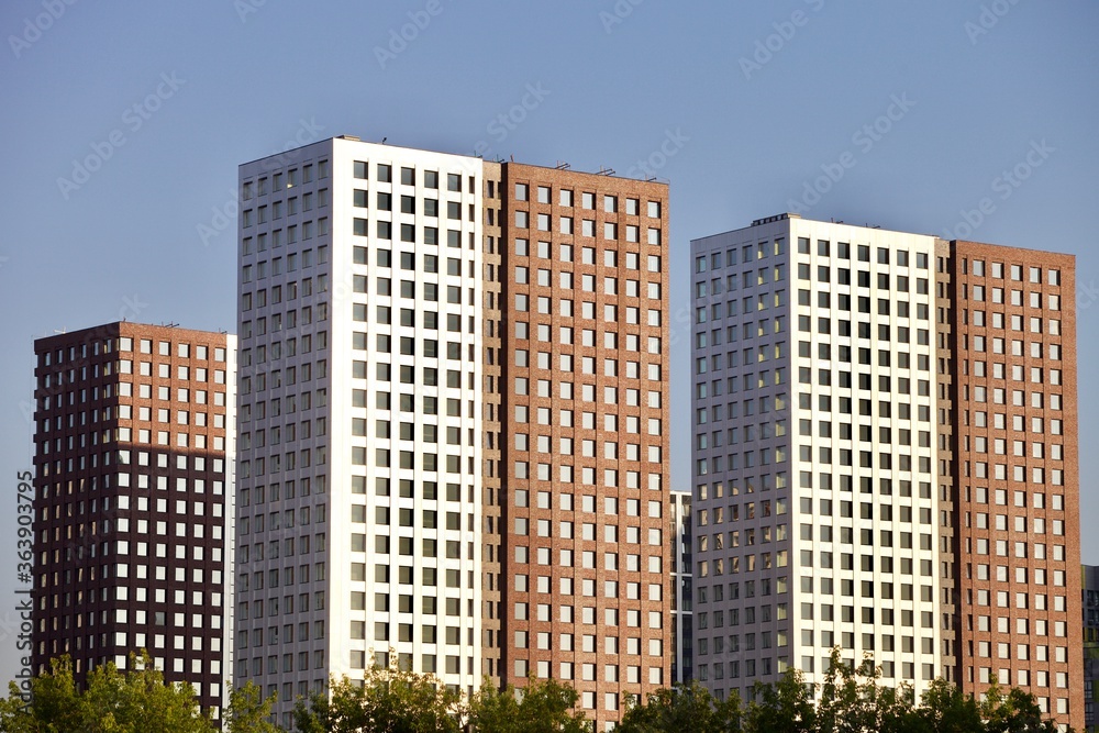 Residential skyscrapers on clear blue sky background. Commercial real estate.  Modern residential city district. Apartment buildings architecture. New Property For Sale. New buildings exterior design.