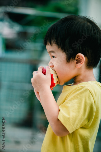 The boy is eating organic apple. He is enjoying it. Fruits are very useful to children.