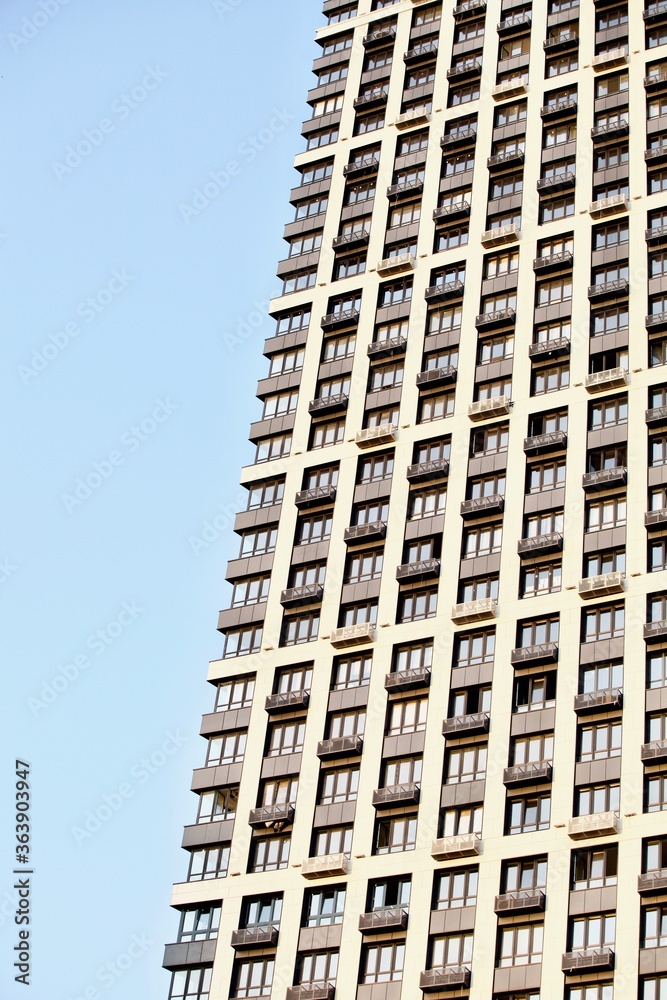 Fototapeta premium Modern residential skyscrapers facade close-up. Commercial real estate. Modern apartment buildings design. Many windows in the wall of a modern house. Residential city tower.
