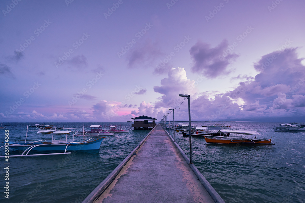 Beautiful colorful sunset on the seashore with fishing boats. Philippines, Siargao Island.