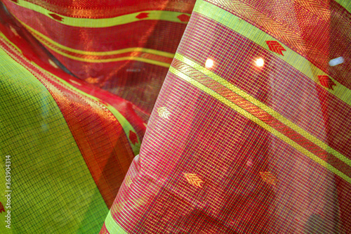 Maheshwari saris in a textile shop, displayed in front of customers. Maheshwar, Madhya Pradesh, India. photo